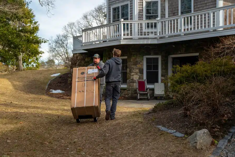 Technicians carrying AC for installation in residential home on Cape Cod, MA.